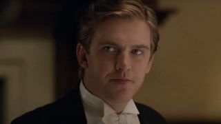 Dan Stevens smirks at the dinner table in Downton Abbey.