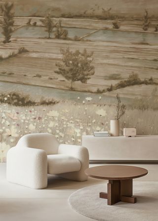 Pelle and Calico wallpaper installation with wallpaper on wall depicting a countryside scene and a white armchair in the room