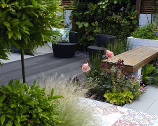 patio with a mix of paving and decking, edged by flowerbeds and a living wall