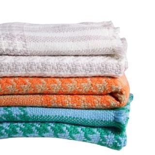 A stack of patterned throws in beige, orange, blue and green