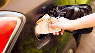 A person shoving money into their car's fuel intake