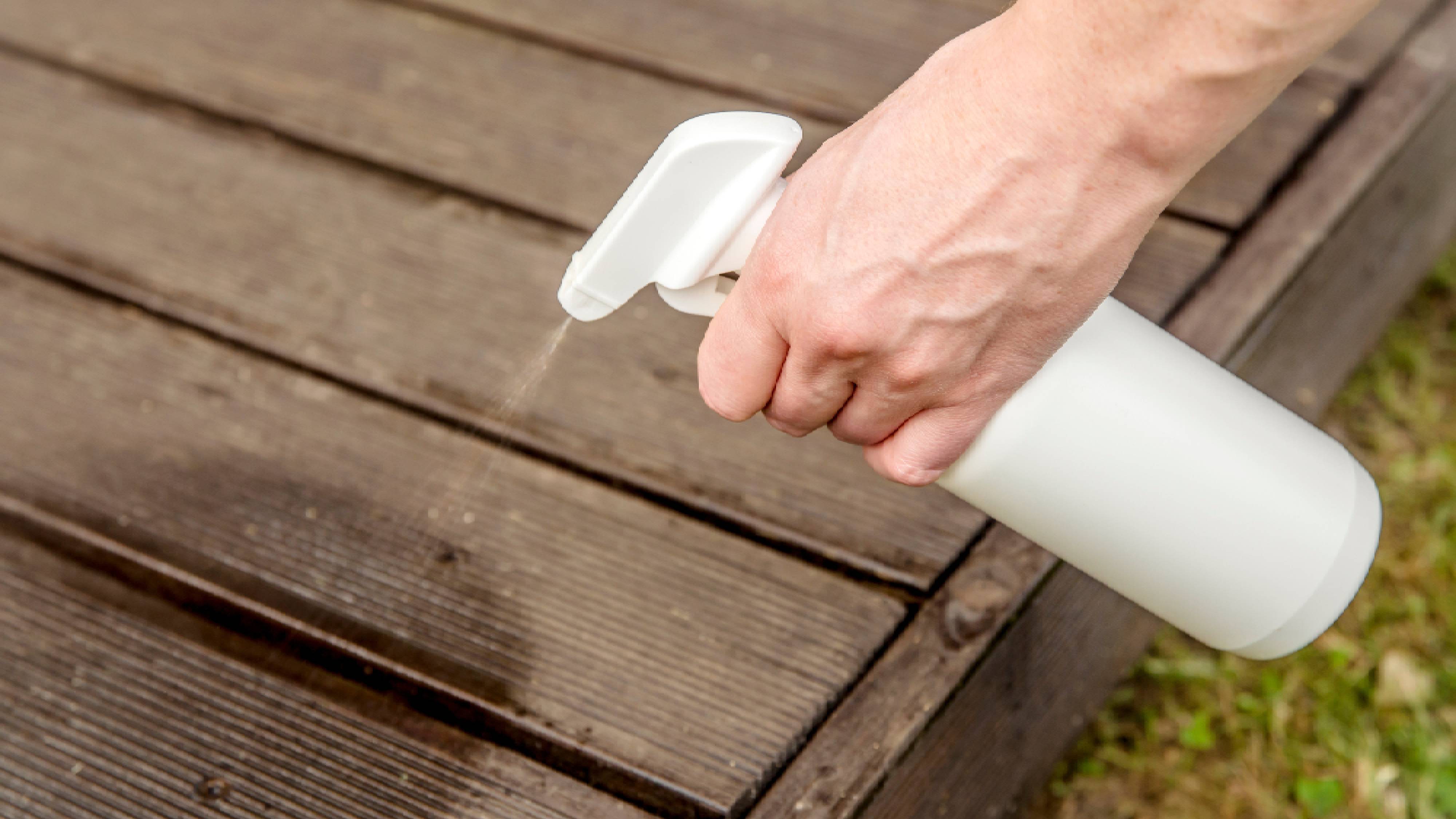 Homemade mosquito repellent spray being sprayed on patio deck