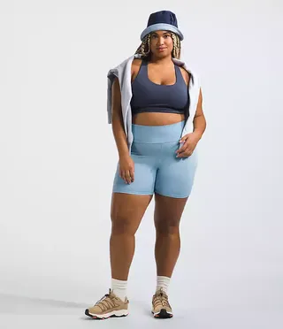 model wears light blue bike shorts and dark blue bra with sneakers and a bucket hat