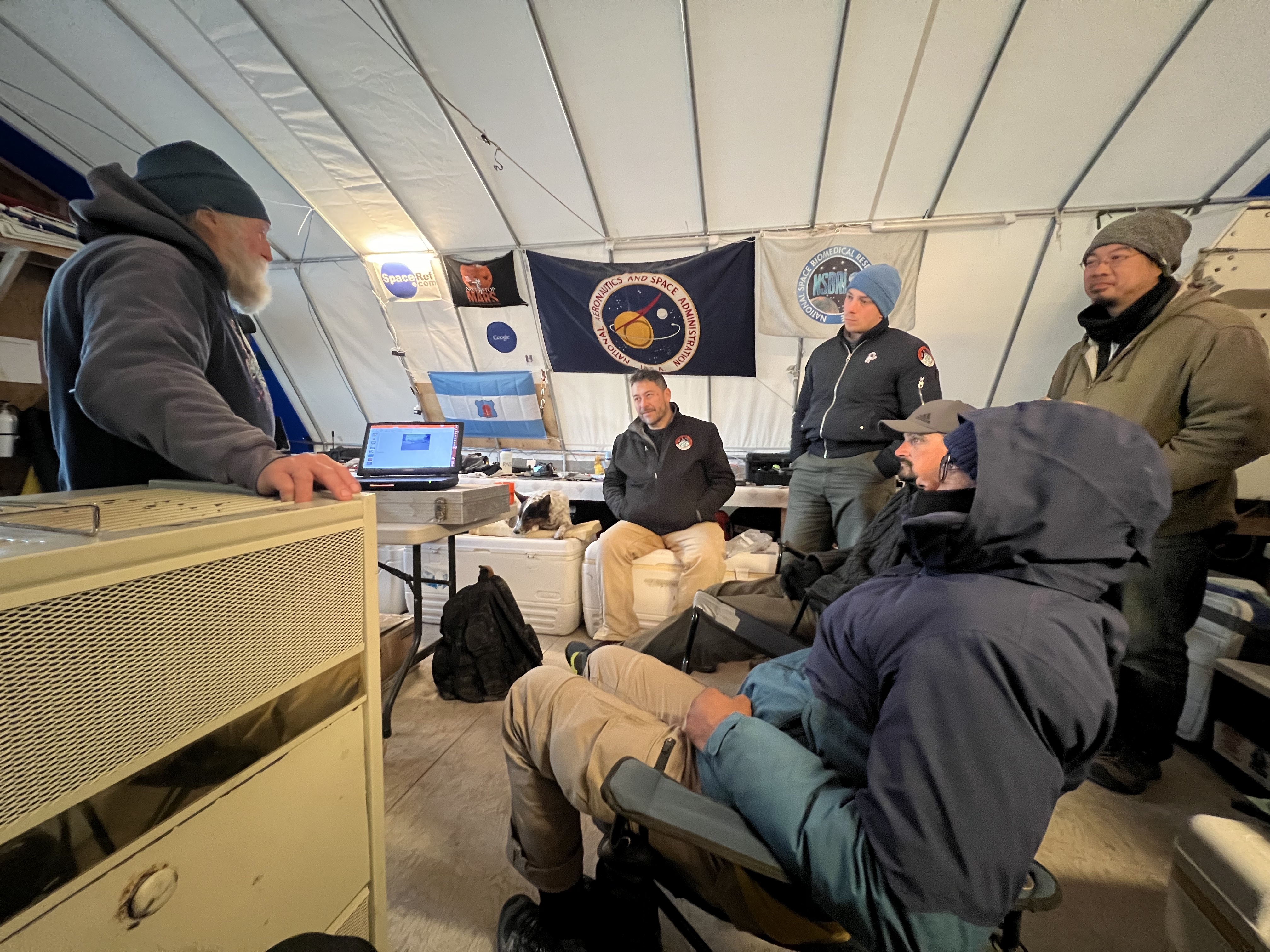 John Schutt, to left, presents to the team about finding meteorites in the Antarctic