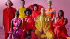 A still from Jaguar's latest ad campaign, picturing eight models wearing red, pink, orange and yellow avant garde outfits. "Copy nothing" is written in white, modern text over the image.