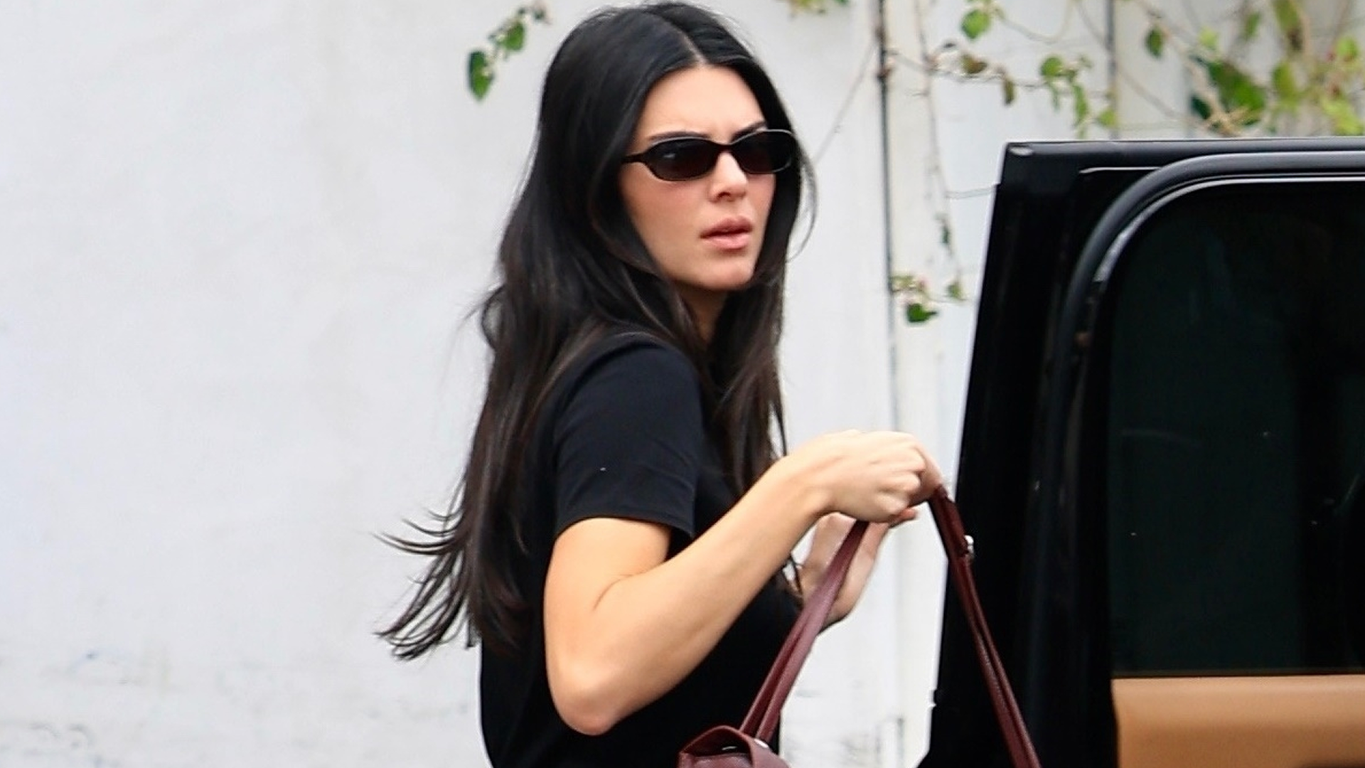 Kendall Jenner wore her white jeans outfit with the Chanel Maxi Flap Bag and matching burgundy ballet flats
