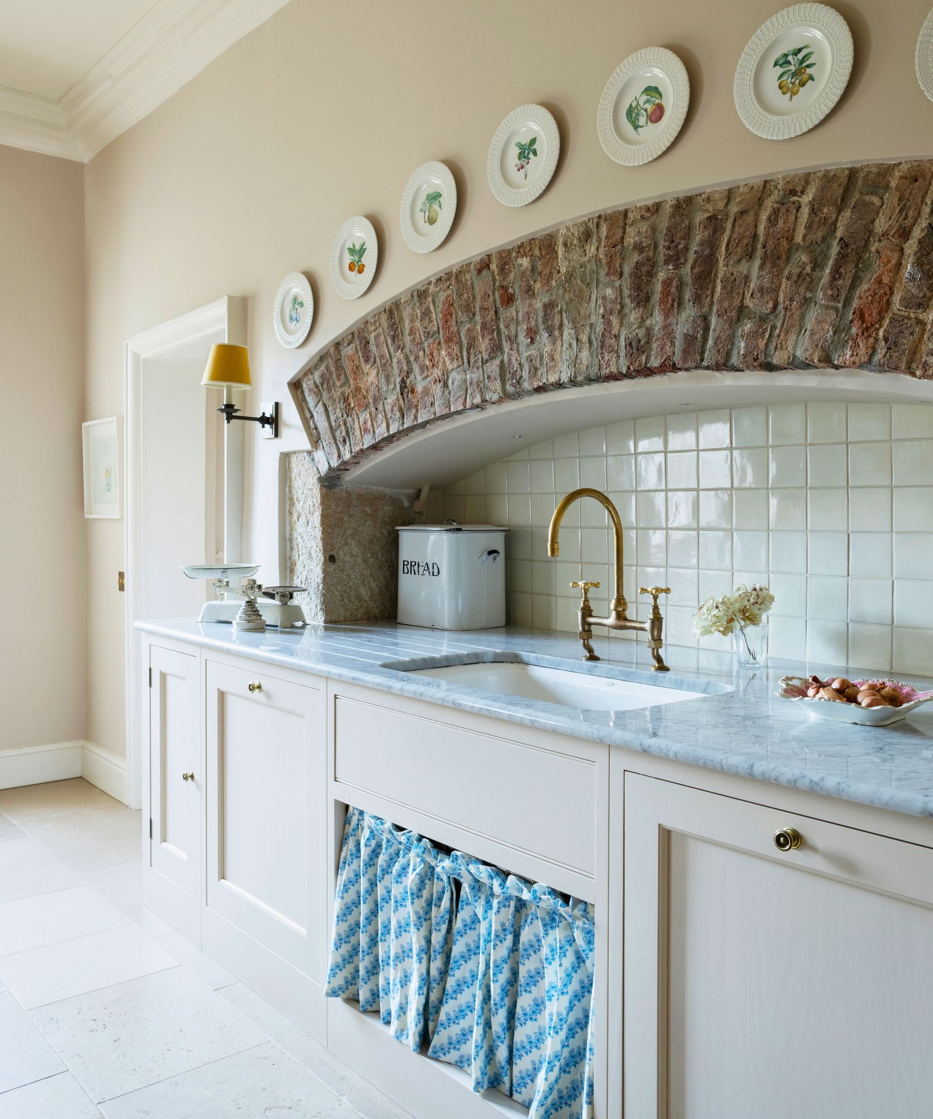 An old kitchen fireplace is repurposed into a scully complete with sink and sink skirt