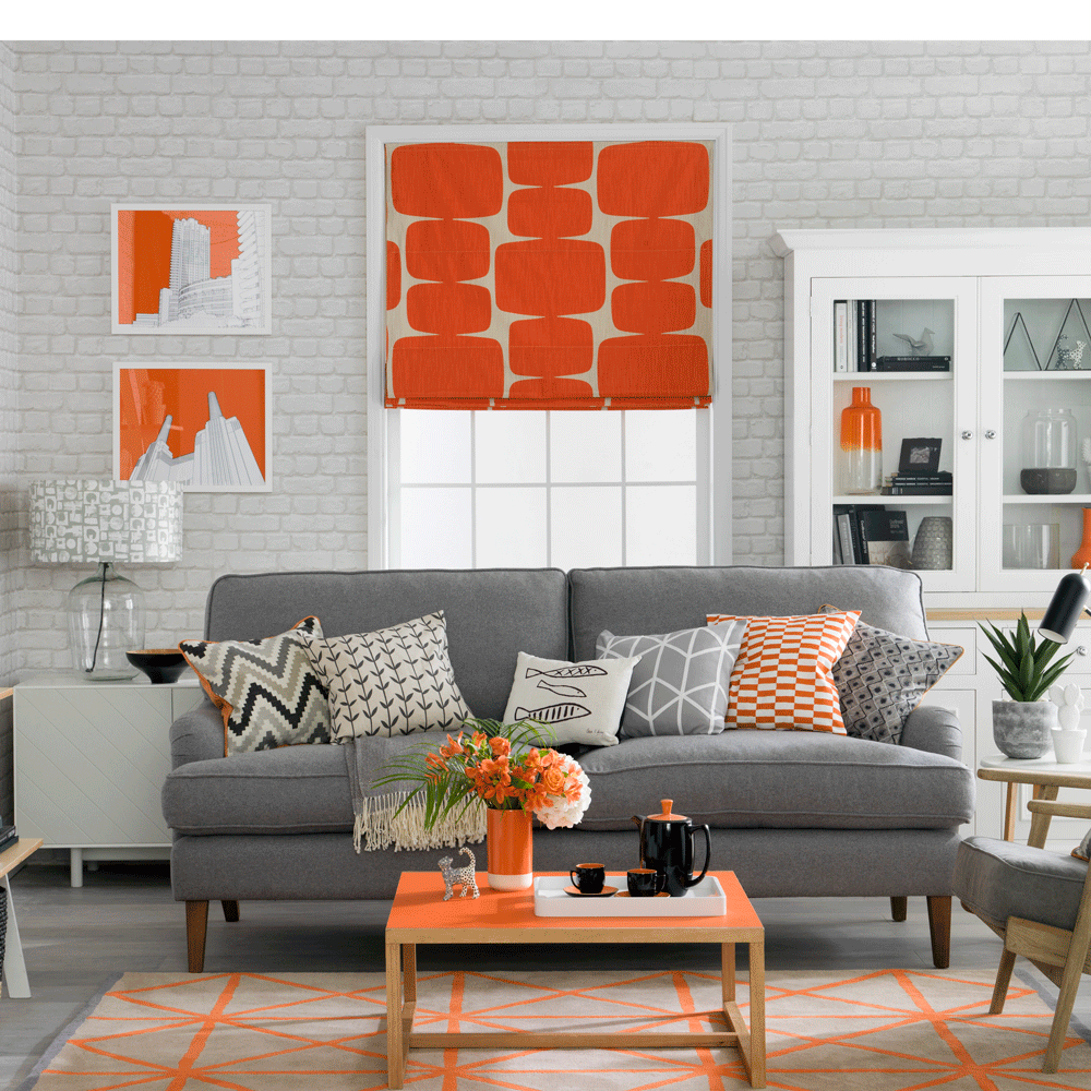 living area with white brick wall and grey sofa with cushions and white window with orange blinds