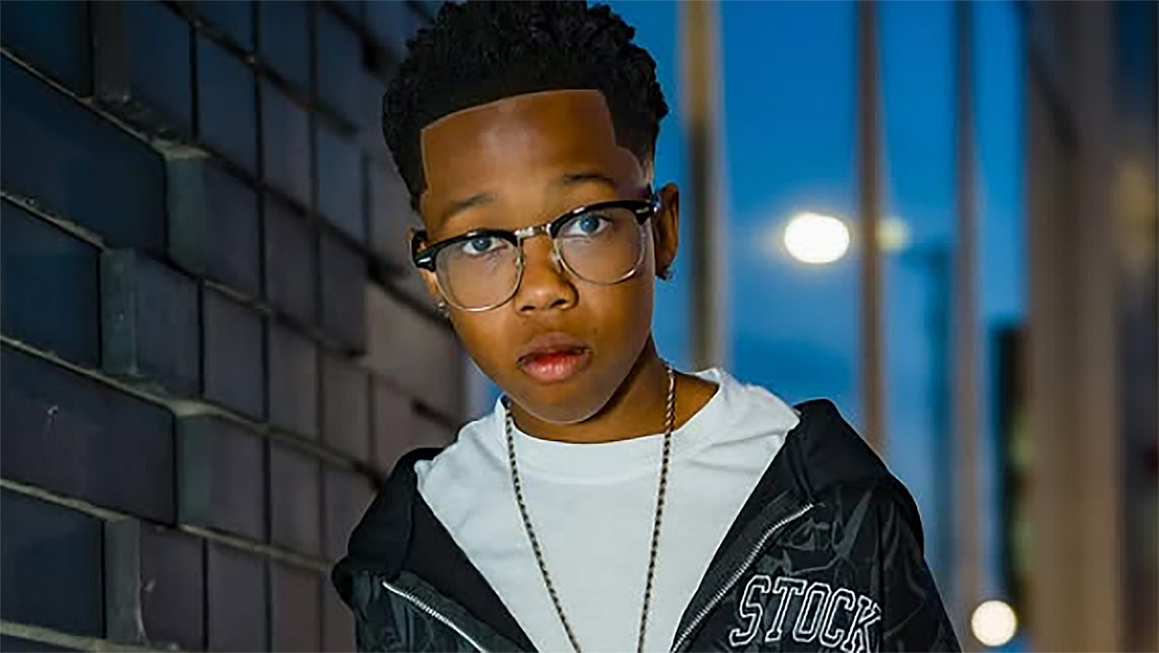 Harper Anthony wearing glasses and staring directly into the camera on a street at night