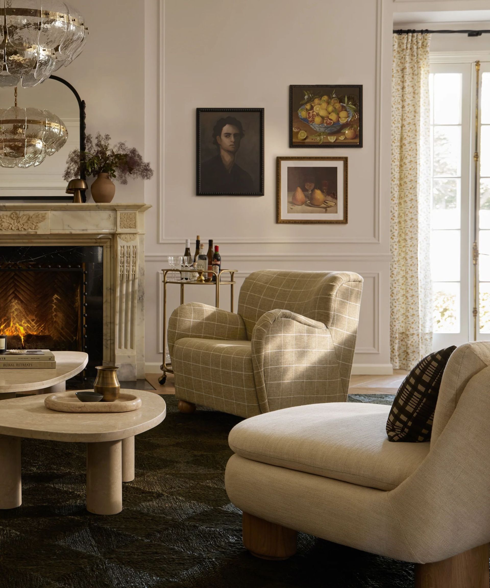 traditional meets contemporary living room with a lit fireplace vintage wall art and two arm chairs