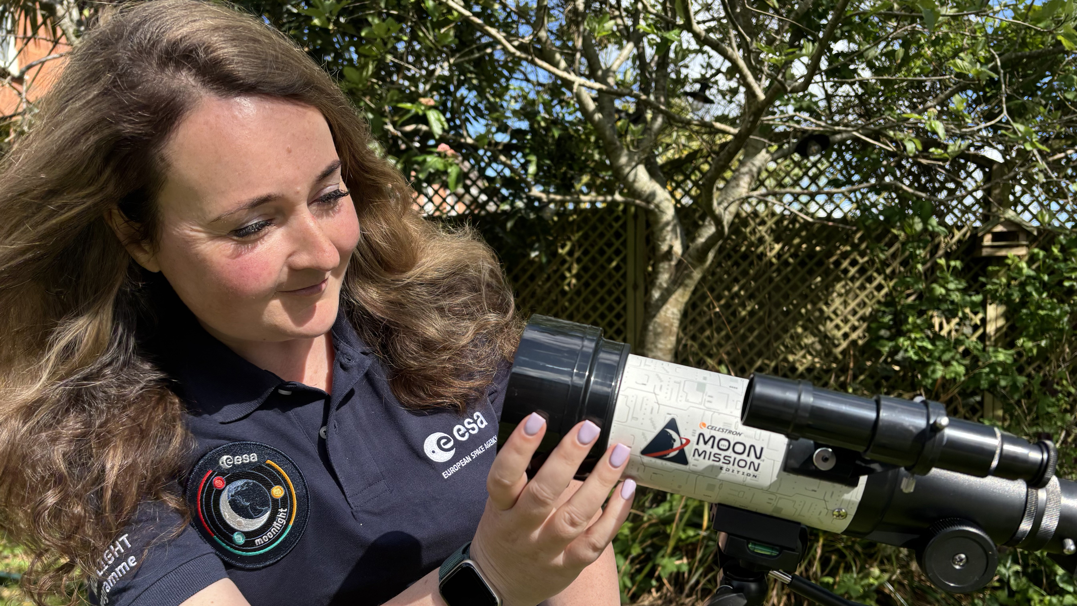 Author Gemma Lavender with a Celestron Moon Mission Travel Scope 70, looking down the objective end.