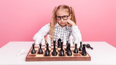 A young girl projects a challenging look while sitting behind a chessboard.