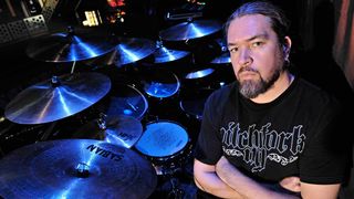 Meshuggah’s Tomas Haake sitting at a drumkit with his arms folded