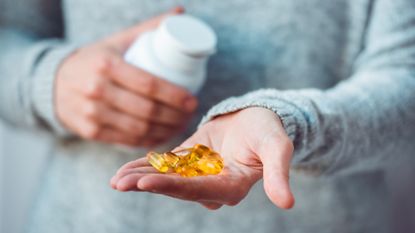Person holding several fish oil supplements in their hand