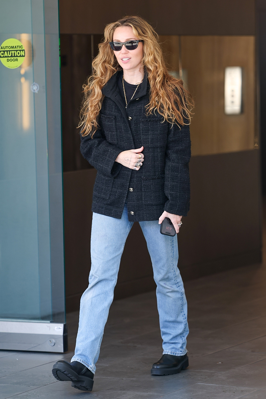 Miley Cyrus wearing a black tweed jacket, straight-leg jeans, and lug-sole boots