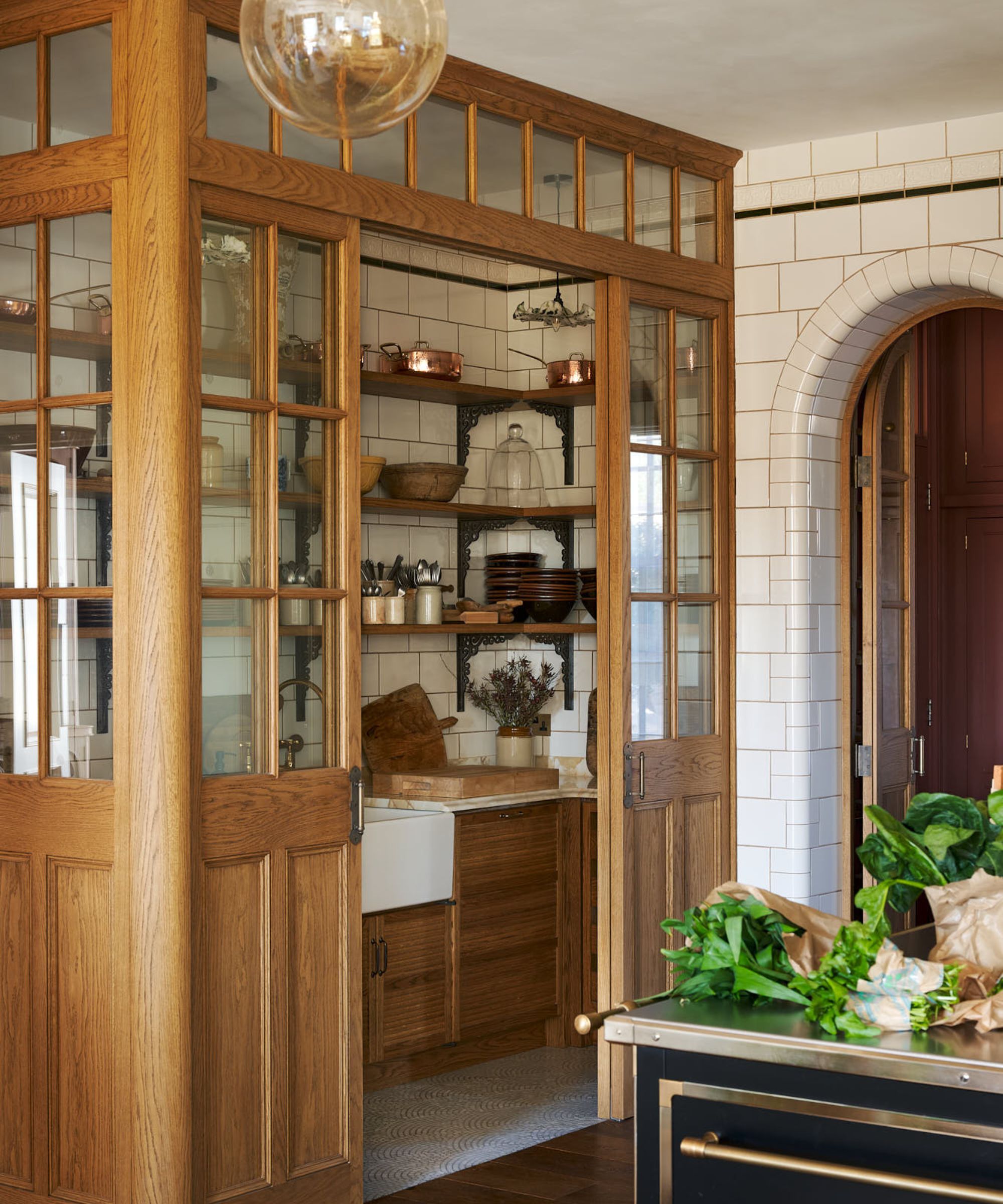 A traditional kitchen with a pantry in the kitchen, framed by wood and glass