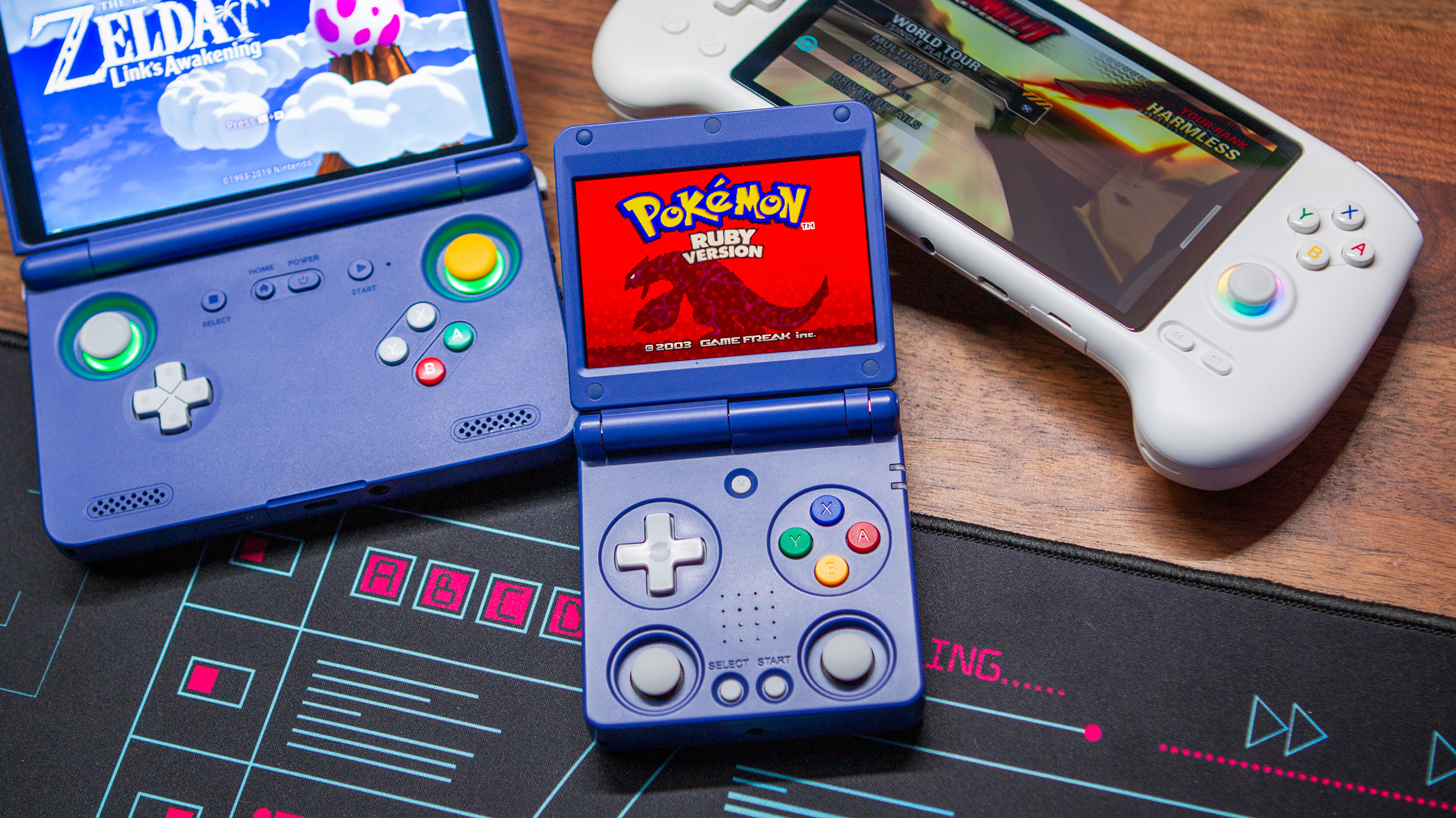 Anbernic RG34XXSP playing Pokemon Ruby surrounded by Retroid Pocket Flip 2 and Anbernic RG557