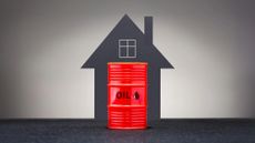 Graphic showing red barrel of oil in front of a grey background and the outline of a house. 