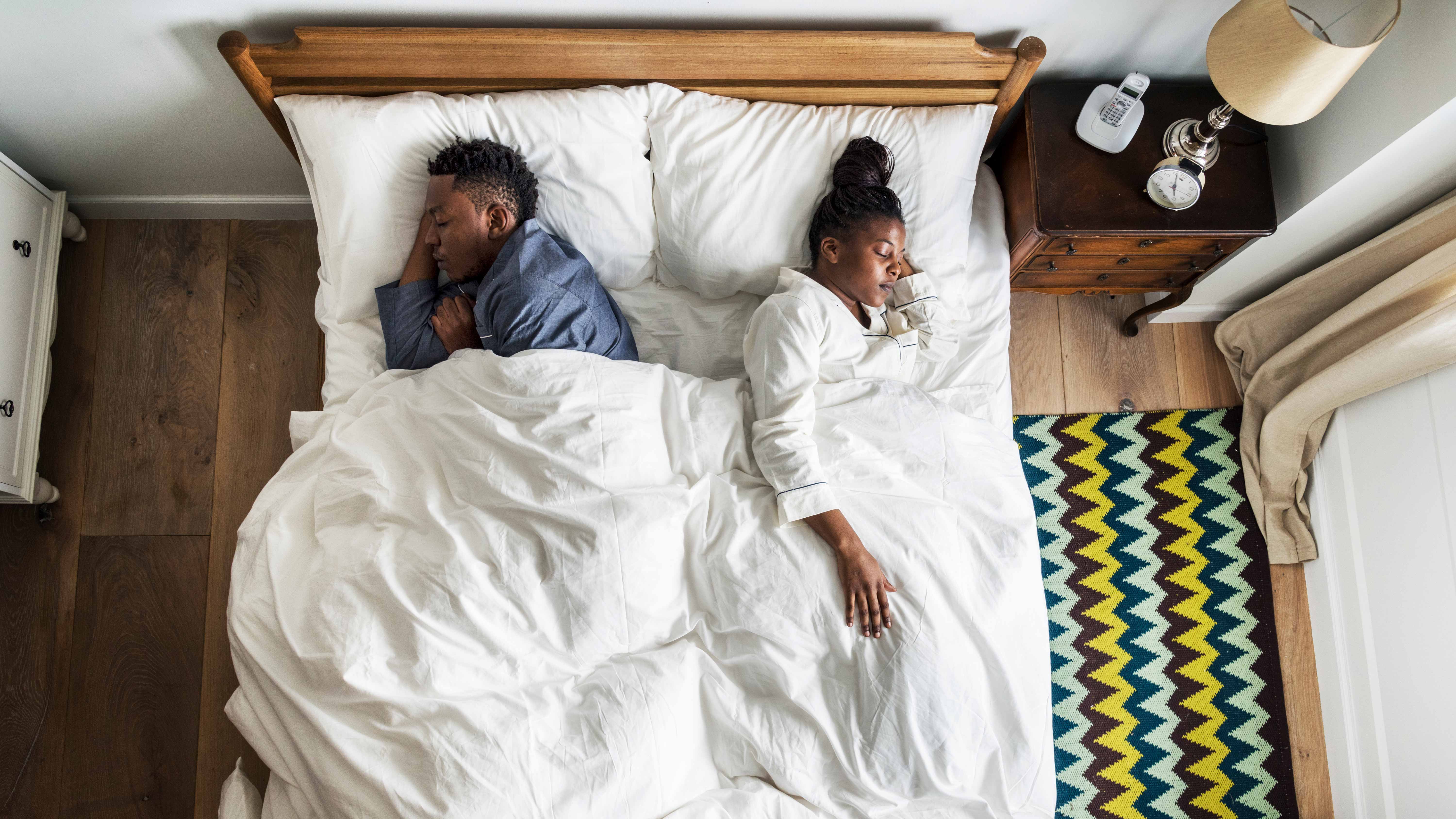 When to change your mattress: couple sleeping in a bed facing different directions