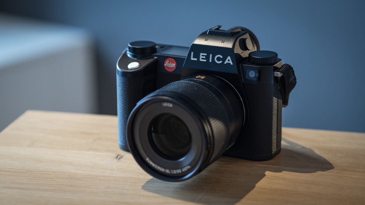 Leica SL3 camera on a wooden surface against a blue background