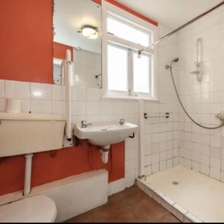 old bathroom with orange walls and pipes showing