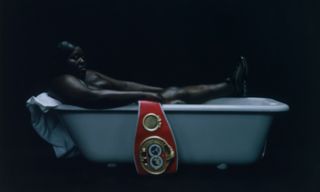 Photo of woman in bath with heavyweight champion belt over side