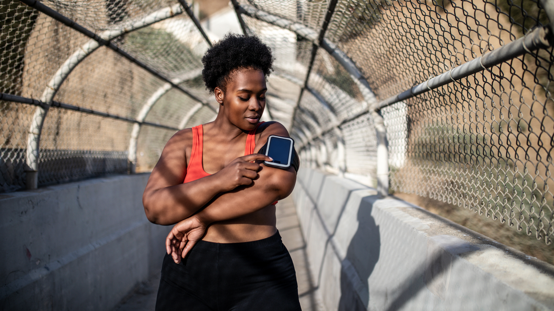 Moters, tikrinančios fitneso stebėjimo priemonę bėgimo metu, vaizdas
