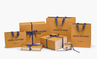Louis Vuitton branded brown carry bags with blue handles and boxes with blue bows around them.