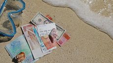 Bank notes, passport and bank card on a sandy beach