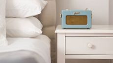 bedroom with white side table and bedding as well as light blues roberts dab radio, n example of the best dab radios