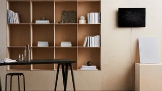 the ikea symfonisk picture frame speaker hanging to the right of a bookshelf