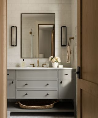 bathroom with gray vanity unit, brass accents, rectangular wall mirror and white wall tiles