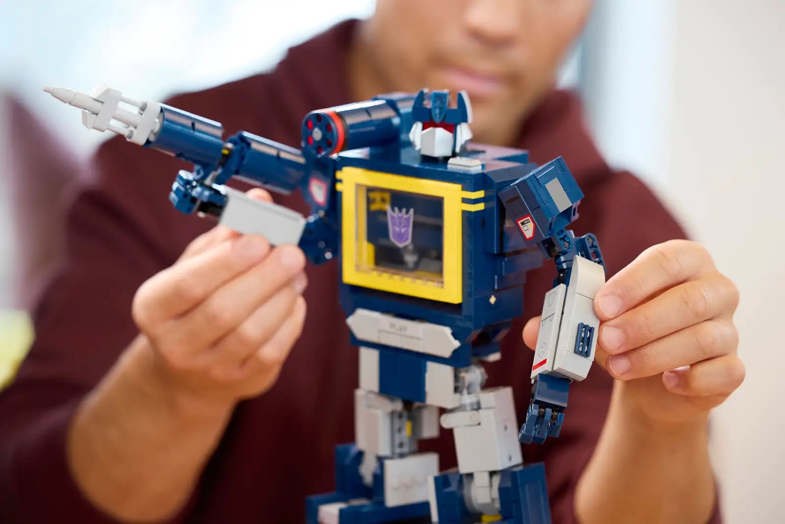 LEGO Transformers Soundwave having arms adjusted by person in a hoodie 