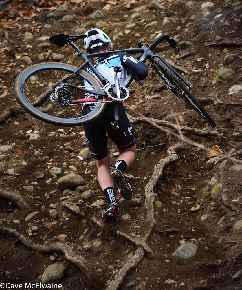 A racer struggles to get climb over the roots and rocks on the steepest run-up