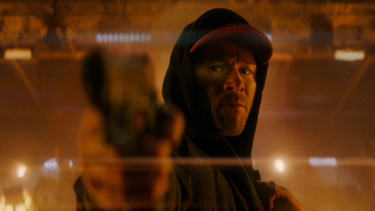 Glen Powell as Ben Richards points a gun at Killian in The Running Man