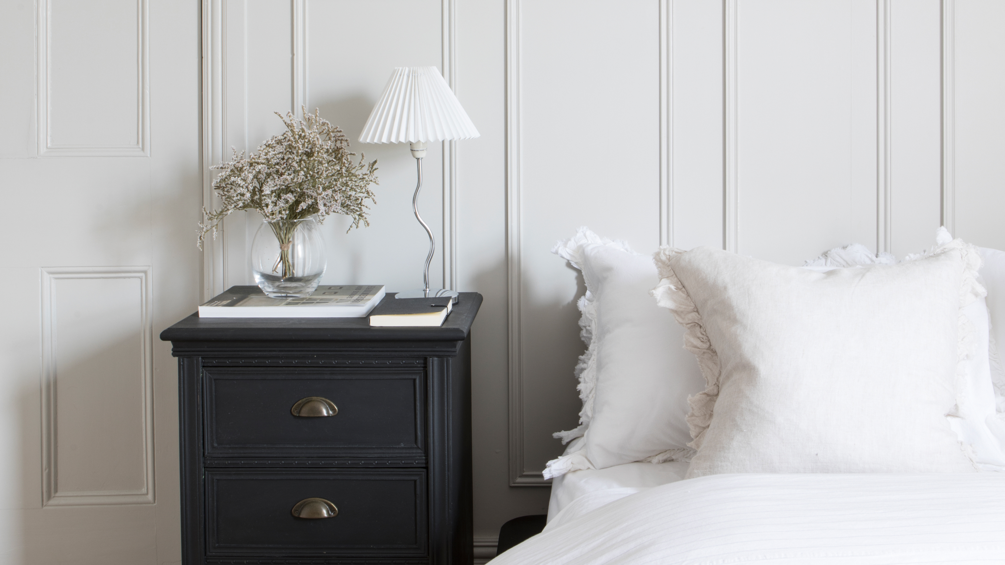 A white bedroom with panelled walls and white bedding
