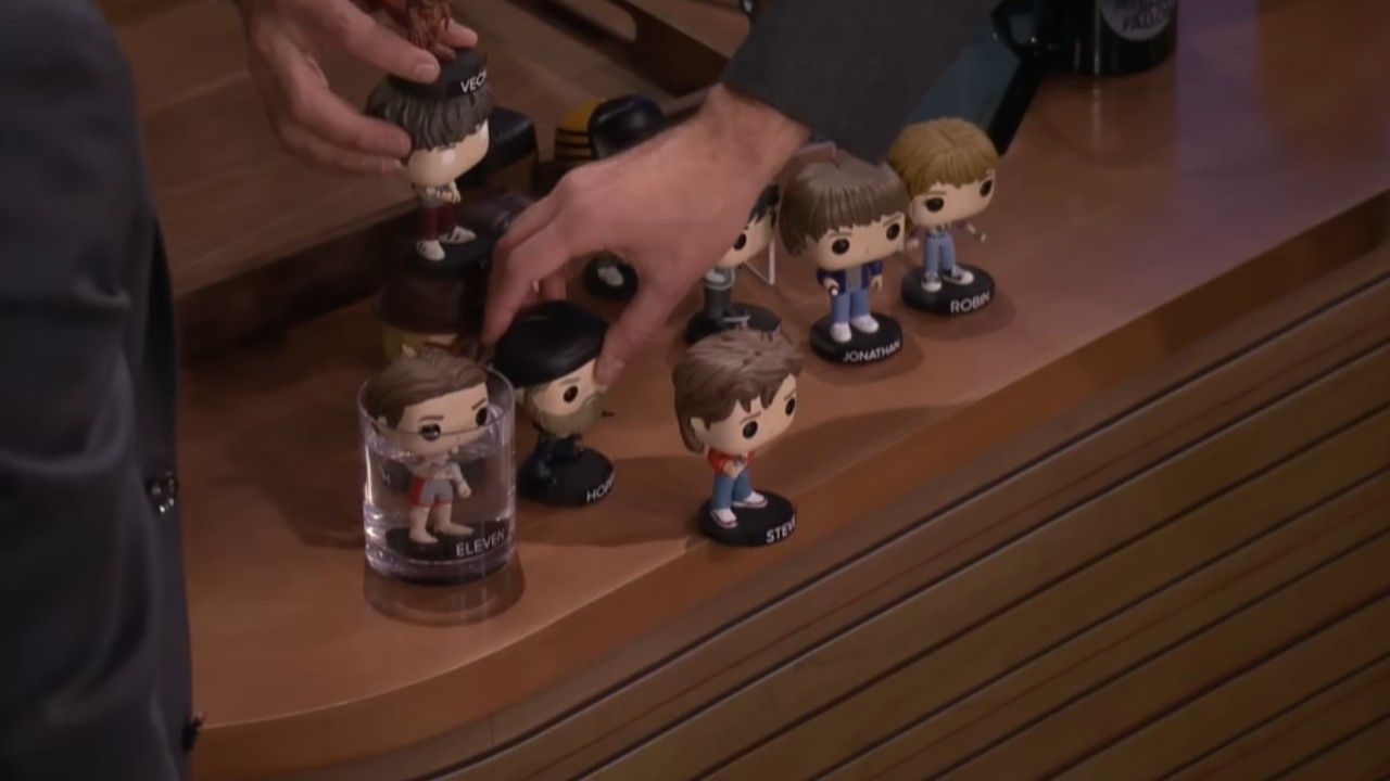 A bunch of Funko Pops on a desk in an episode of The Tonight Show, Steve is on the edge of the desk. 