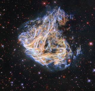 The colorful strands of gas glowing in orange and blue are the remains of a supernova triggered when a massive star reached the end of its life.