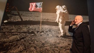 Apollo 11's Buzz Aldrin salutes next to a picture of himself on the moon on July 23, 2019, approximately 50 years after he participated in the first-ever lunar landing. The picture was taken at an Apollo 11 exhibit at the Richard Nixon Presidential Library and Museum near Los Angeles.