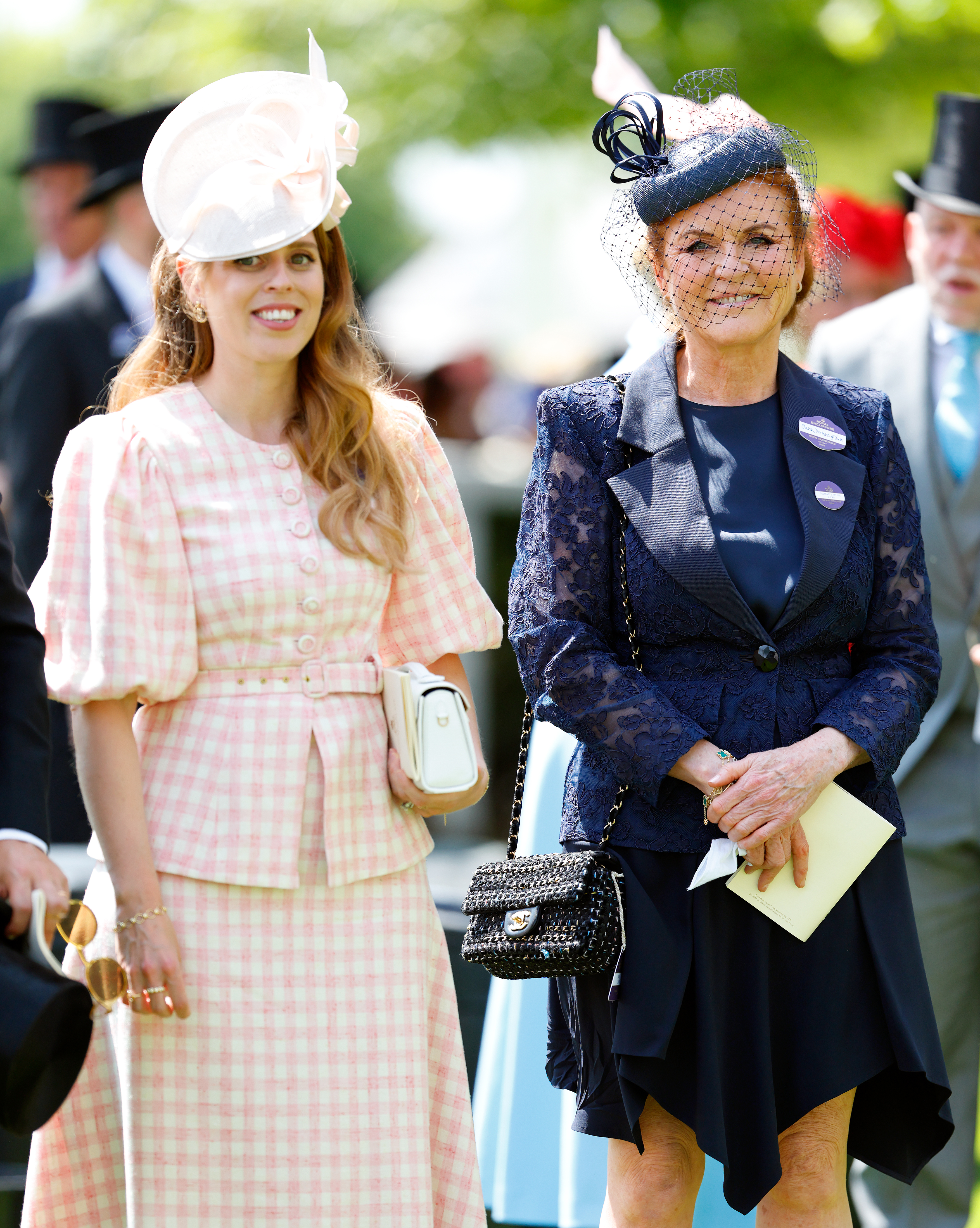 Sarah Ferguson wearing a blue dress and hat and Princess Beatrice in a pink gingham outfit smiling at Royal Ascot