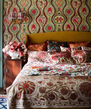 Maximalist wallpaper behind bed in bedroom with lots of country floral prints