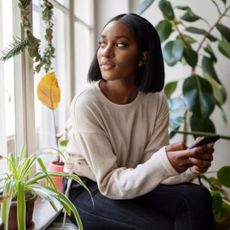 How to reframe negative thoughts: Woman at home looking outside window