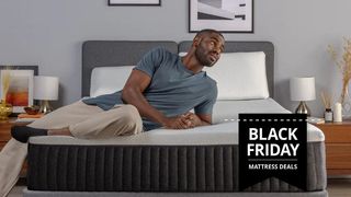 Man in a blue t shirt lies across the Emma Hybrid Comfort mattress, with black friday mattress sales tag overlaid on image