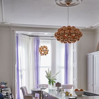 room with copper spherical ceiling lamps and white window with curtains
