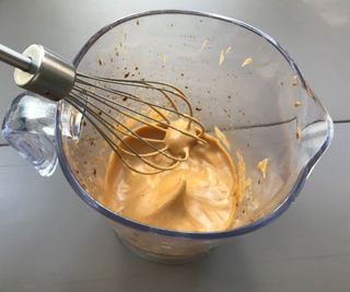 Dalgona coffee being whipped in a plastic pitcher