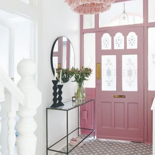 Hallway with a pink front door, a staircase and a statement chandelier