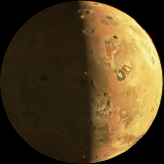 A view of Io. The right side is lit and the left is shadowed. The moon appears to be yellowish with swirly designs.