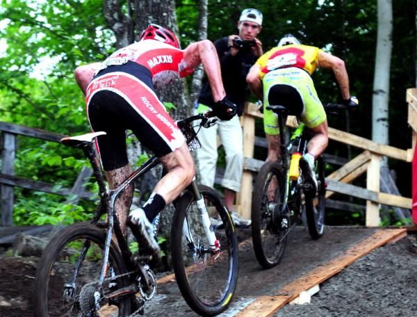Riders head up a steep wooden ramp.
