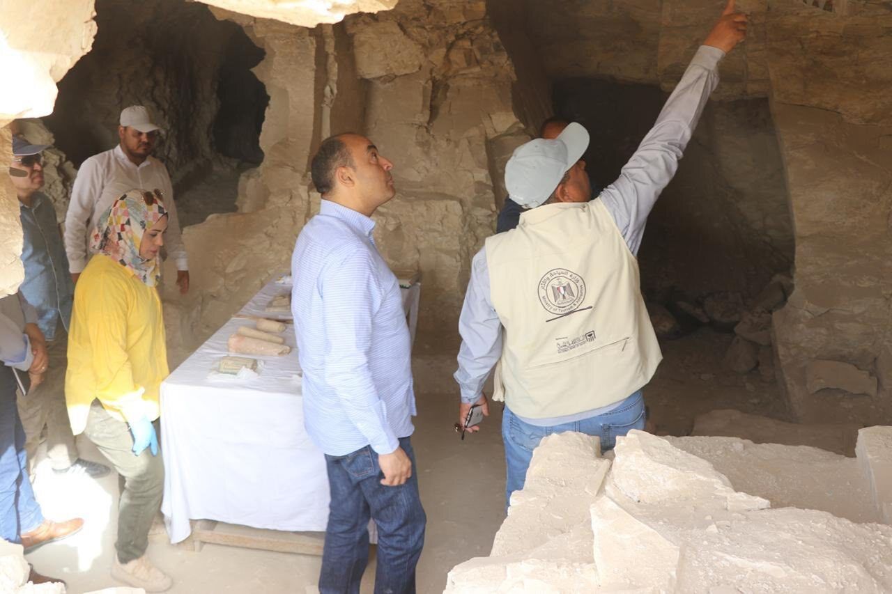 a group of people stand inside an excavated tomb