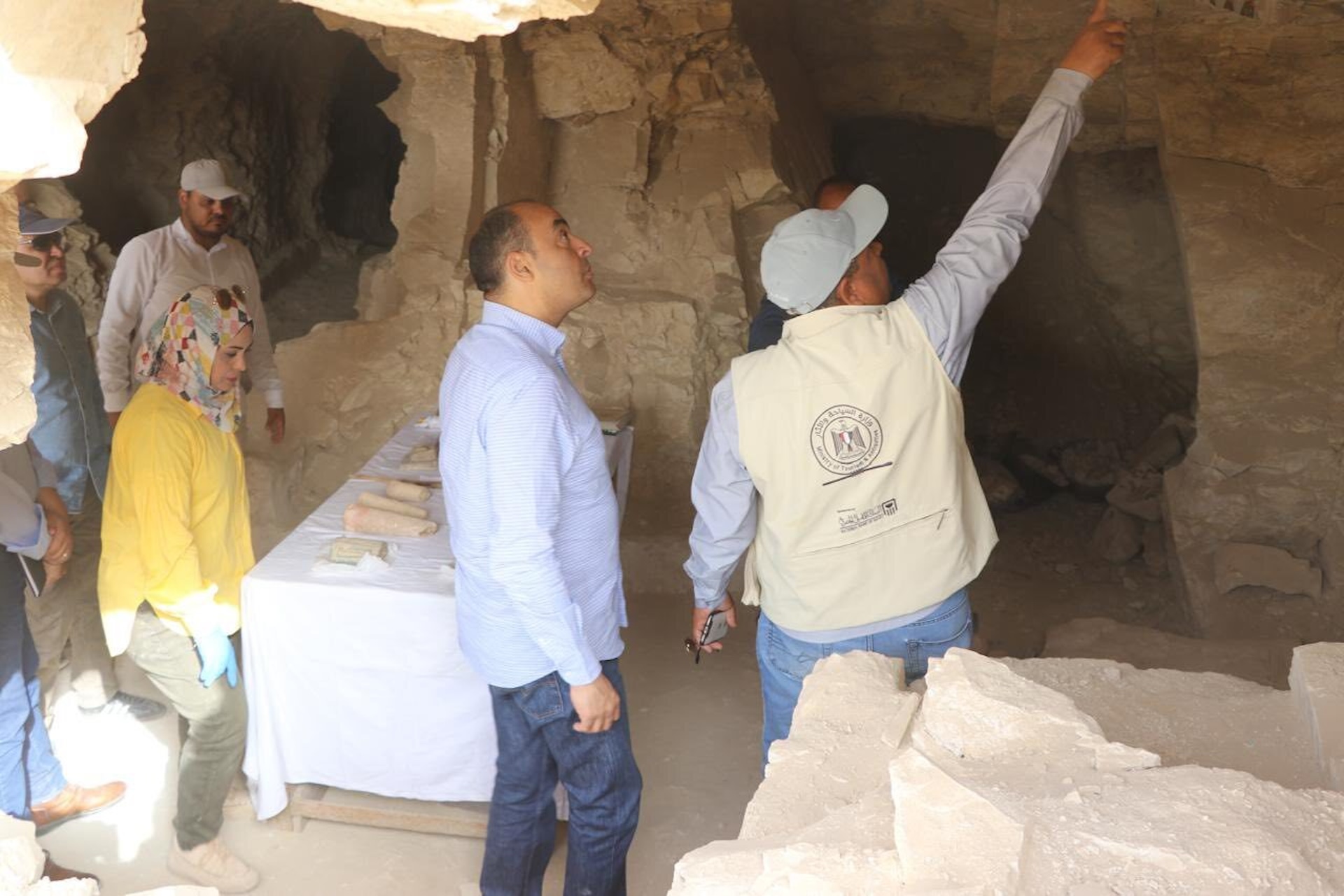 a group of people stand inside an excavated tomb